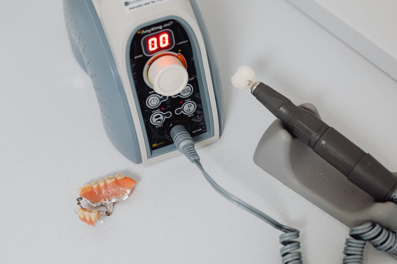 Close-up of dental machine and denture on countertop, showcasing dental technology.